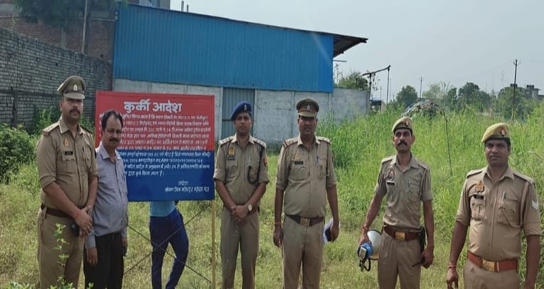 अवैध अचल संपत्ति के खिलाफ कुर्की की कार्रवाई करते पुलिस अधिकारी