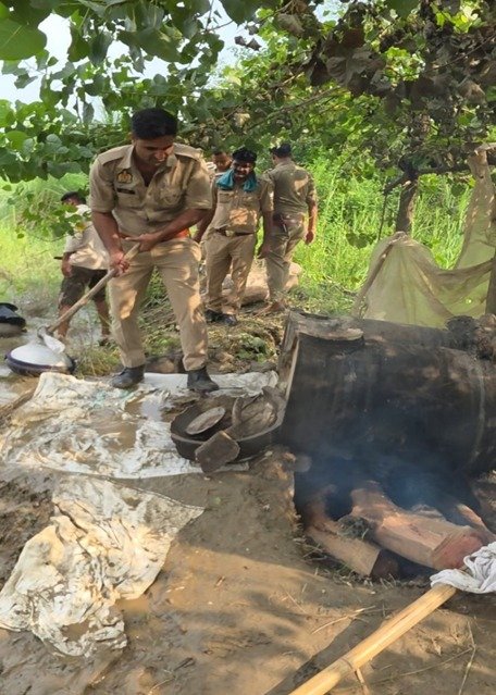 अवैध शराब की भट्टी तोड़ते पुलिसकर्मी