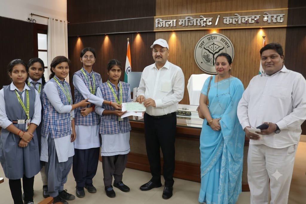 बाढ़ पीड़ितों की मदद हेतु जिलाधिकारी को इक्कीस हजार रुपये की राशि सौंपती आर एम स्कूल की छात्राएं
